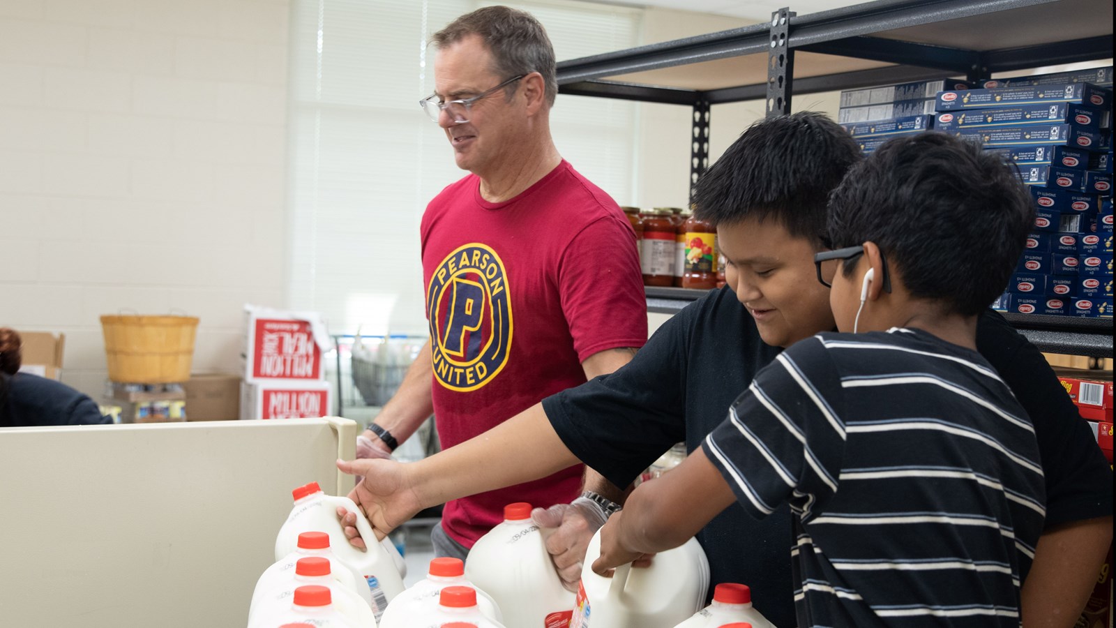 Pearson Principal Dean Yoder and students help stock fridge with milk inside The Fresh Market.
